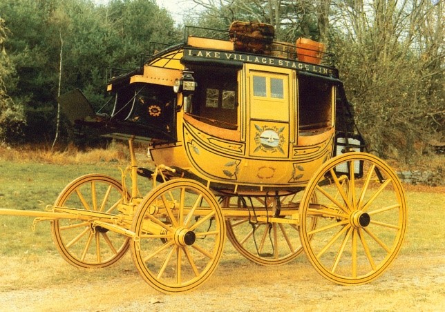A gold stage coach on a lawn.