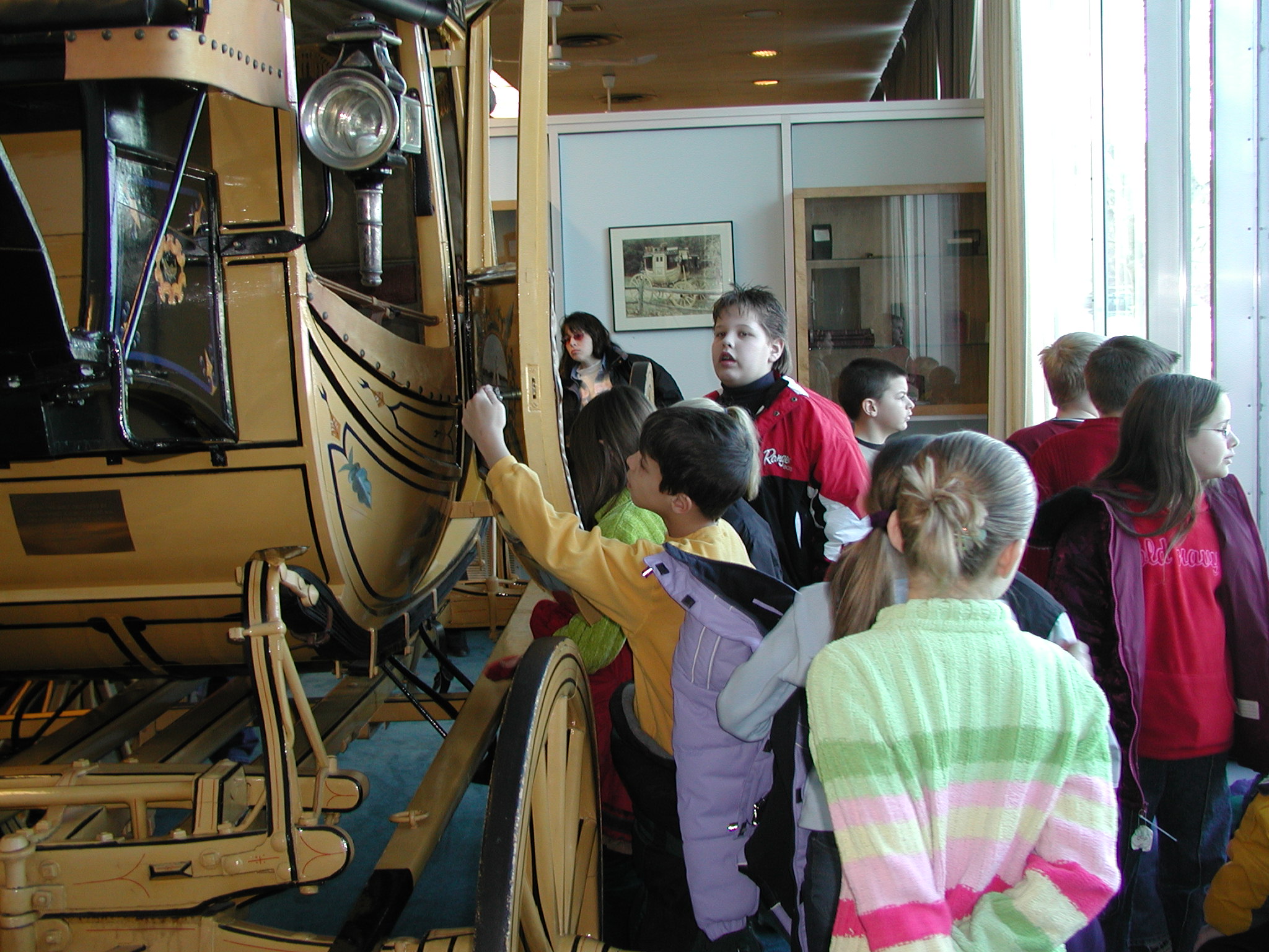 A group of individuals standing in front of a gold stage coach. 