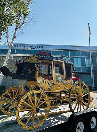 A gold and maroon stage coach on a trailer in front of a building