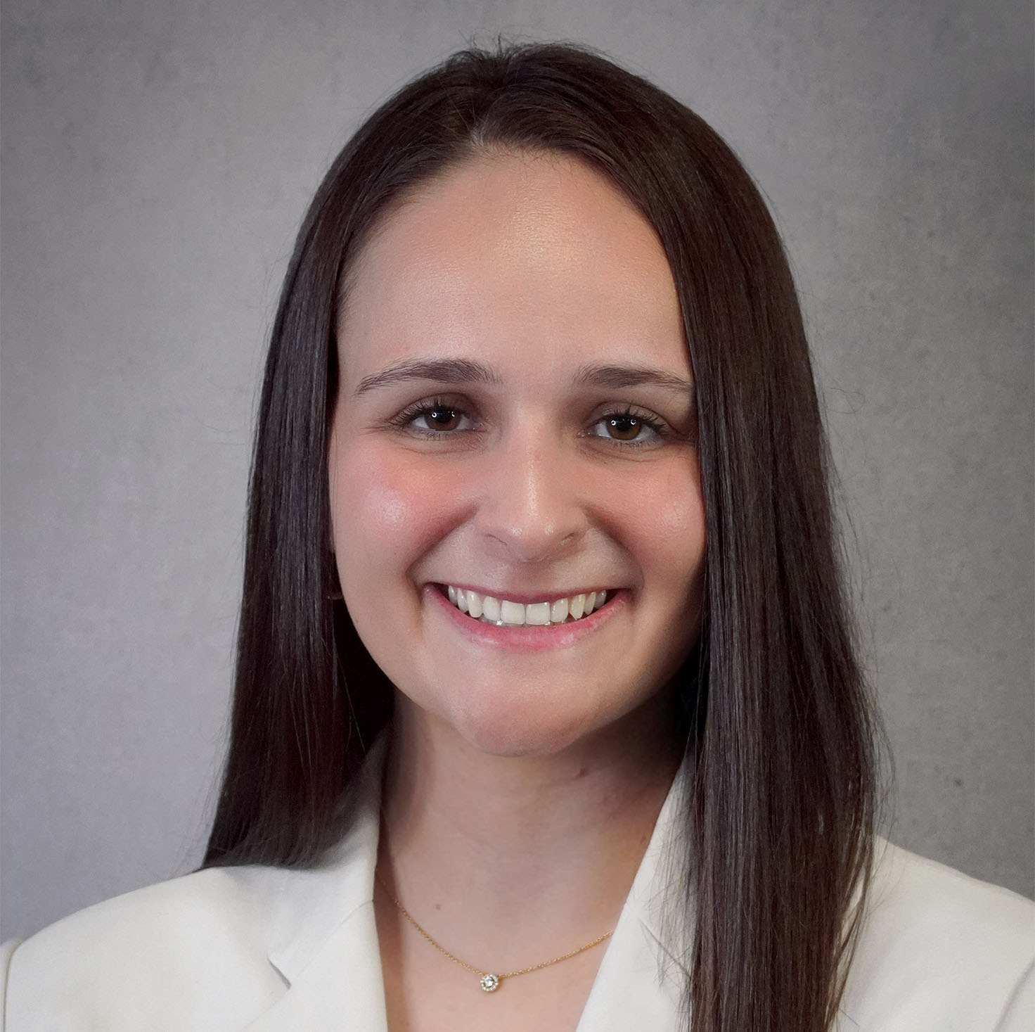 An individual with long black hair wearing a white suit coat.