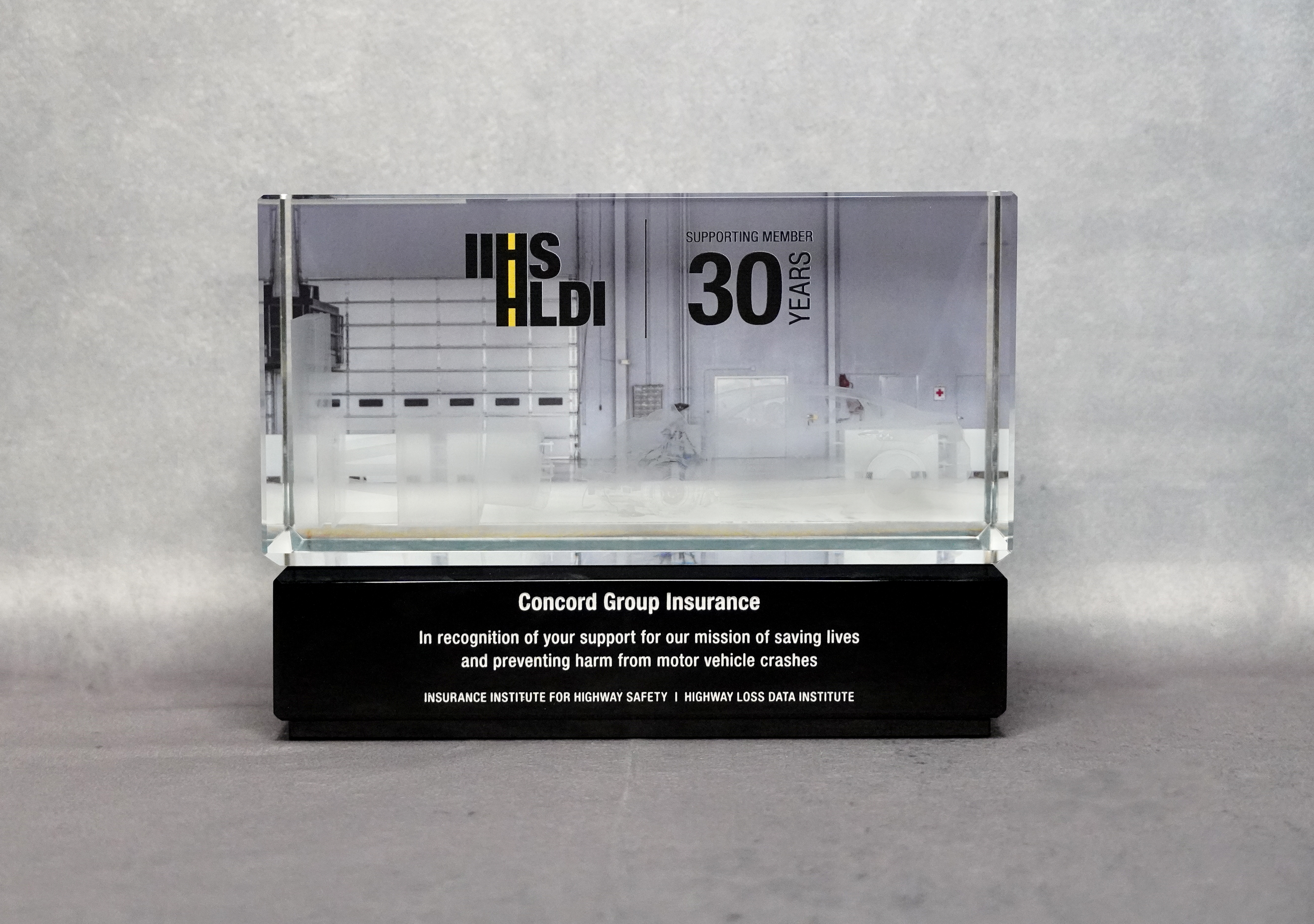 A glass trophy in front of a grey back drop.