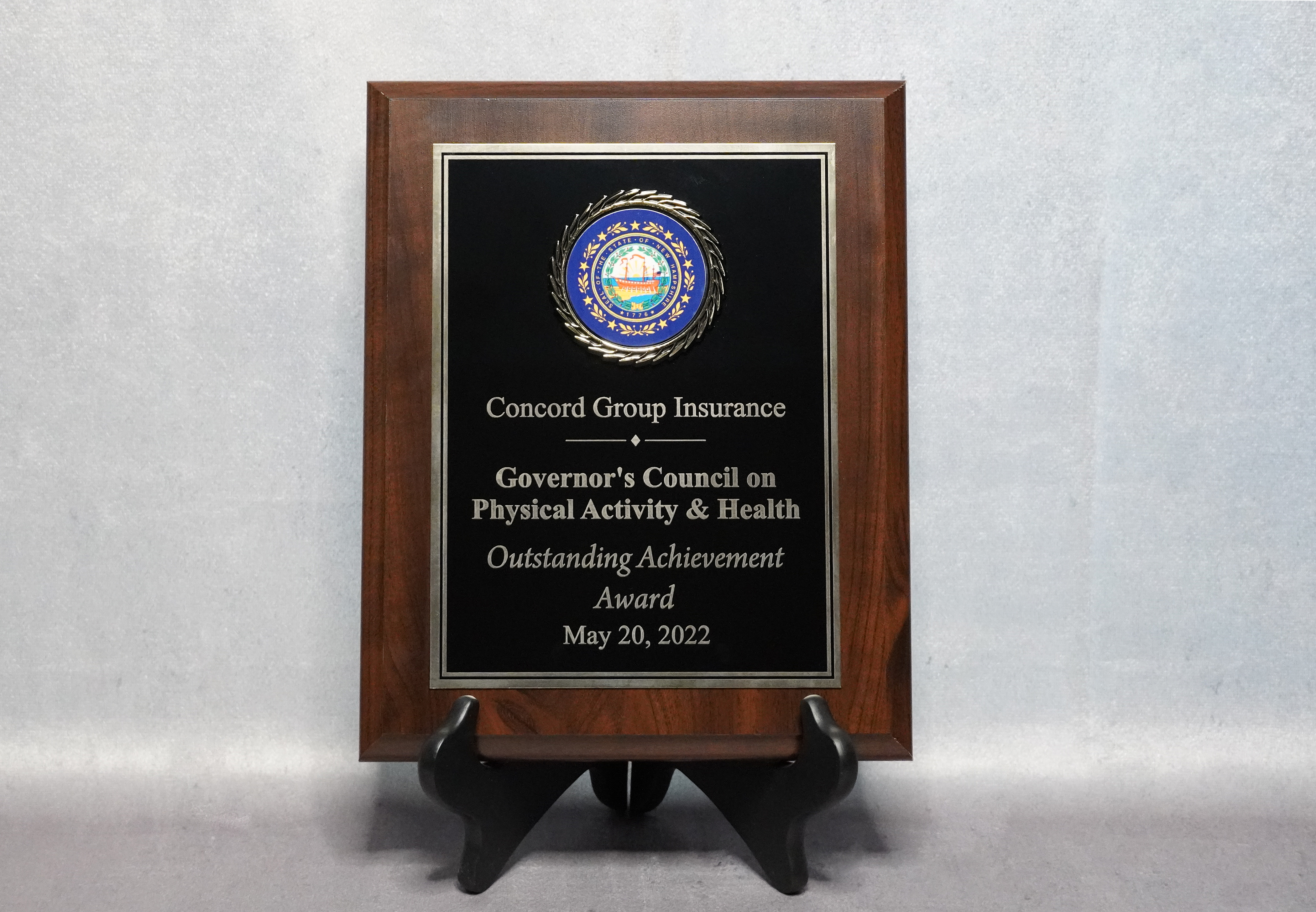 A plaque on a stand in front of a grey back drop.