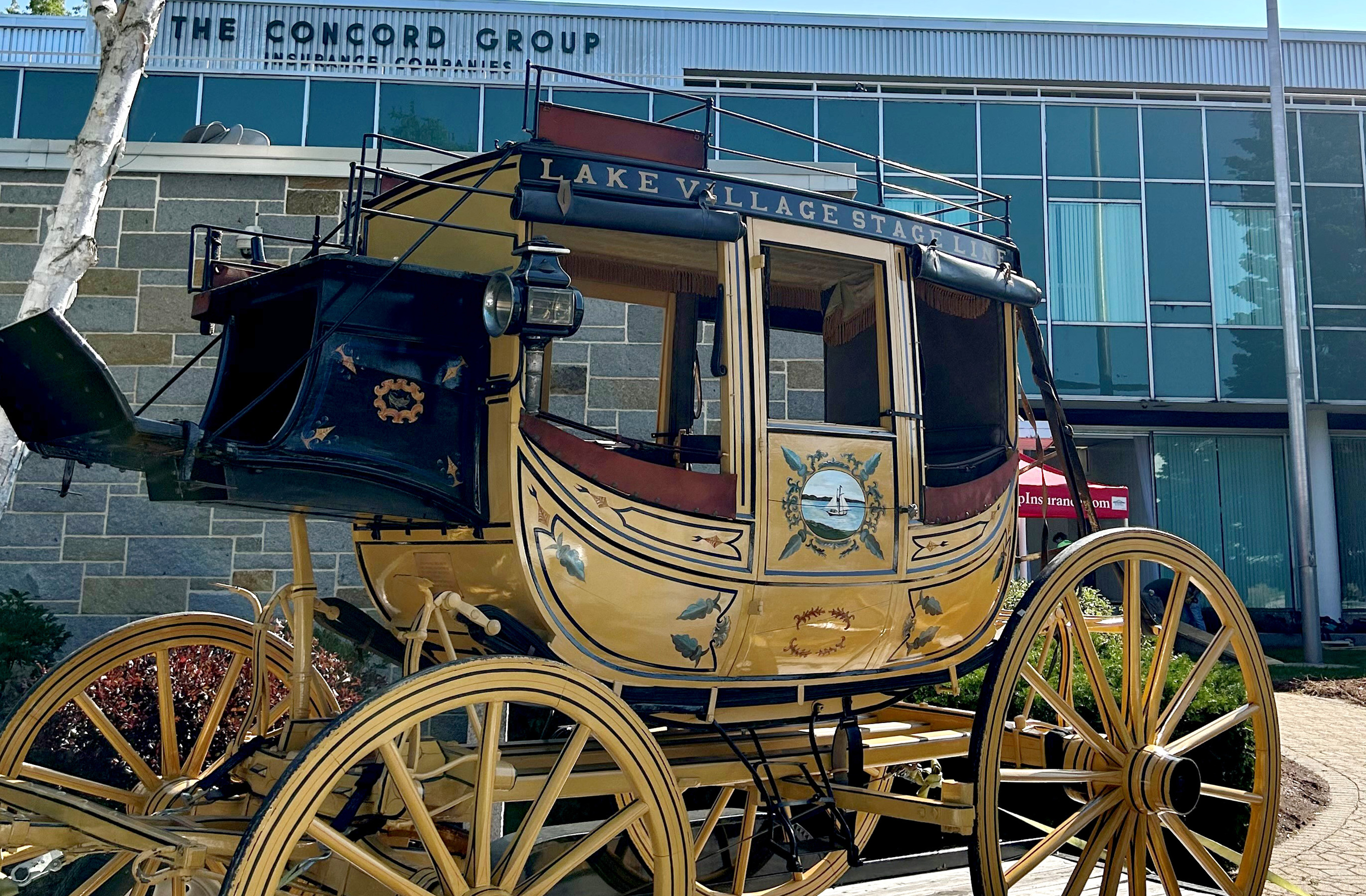 A gold and maroon stage coach in front of a building.